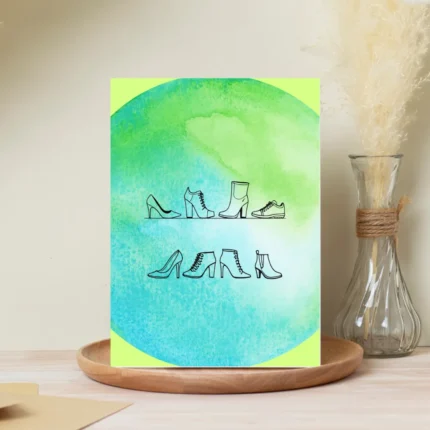 Minimalist line art illustration of various women's shoes, including stilettos, ankle boots, and sneakers, centered over a vibrant green and teal watercolor circle on a white greeting card.