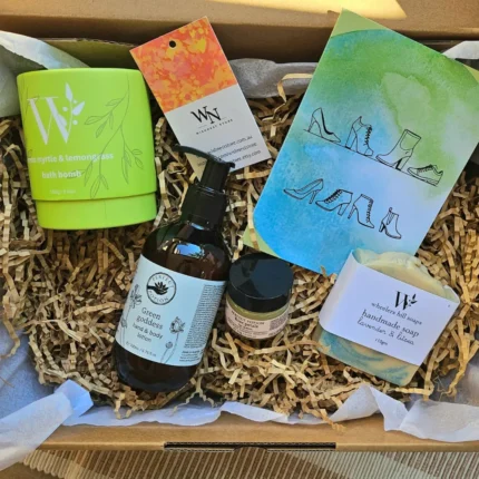 Overhead view of a sustainable Australian gift box containing Perfect Potion Green Goddess lotion, Lemon Myrtle bath bomb, and Wheelers Hill handmade soap on brown crinkle paper.