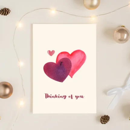 Close-up of a hand-painted heart card next to a colorful beaded bracelet and white ribbon.