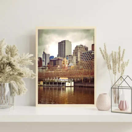 A vibrant photograph of the Melbourne skyline from the Yarra River featuring the South Wharf district and historic architecture.
