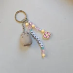 lose up of an Australian-made, sustainable Pusheen keychain featuring a pastel pink and yellow flower charm and recycled acrylic beads.