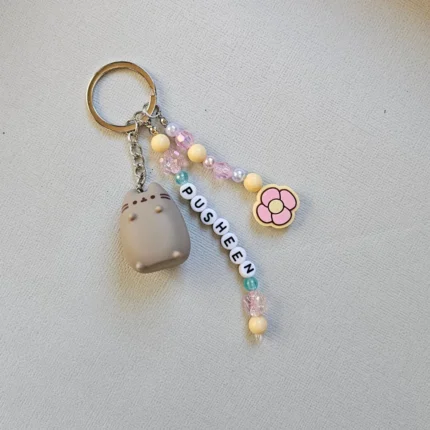 lose up of an Australian-made, sustainable Pusheen keychain featuring a pastel pink and yellow flower charm and recycled acrylic beads.