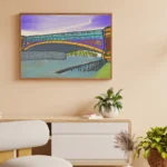 Framed urban cityscape artwork featuring the Yarra River bridge displayed as office wall art next to a minimalist desk setup.