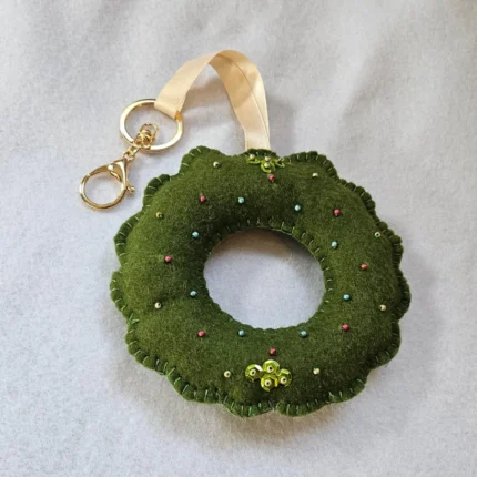Handmade felt bag charm ornament hanging on a designer handbag showing texture.
