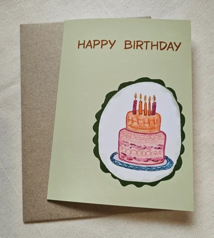 Hand-drawn birthday cake card with five candles on a sage green Happy Birthday card, kraft envelope behind