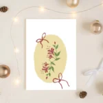 Honeysuckle and red bow greeting card styled with Christmas baubles and fairy lights