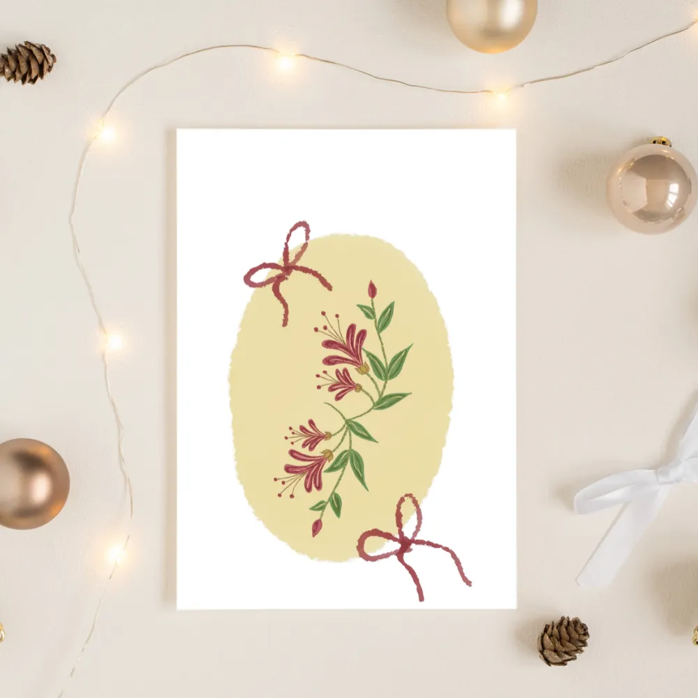 Honeysuckle and red bow greeting card styled with Christmas baubles and fairy lights